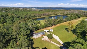 A residential property with a large pond, surrounded by dense forest, and a house with a visible deck and solar panels. - A Cozy Place - Country/Beach Living (Beaufort)