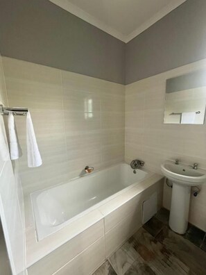 Un baño con bañera, lavabo y espejo.