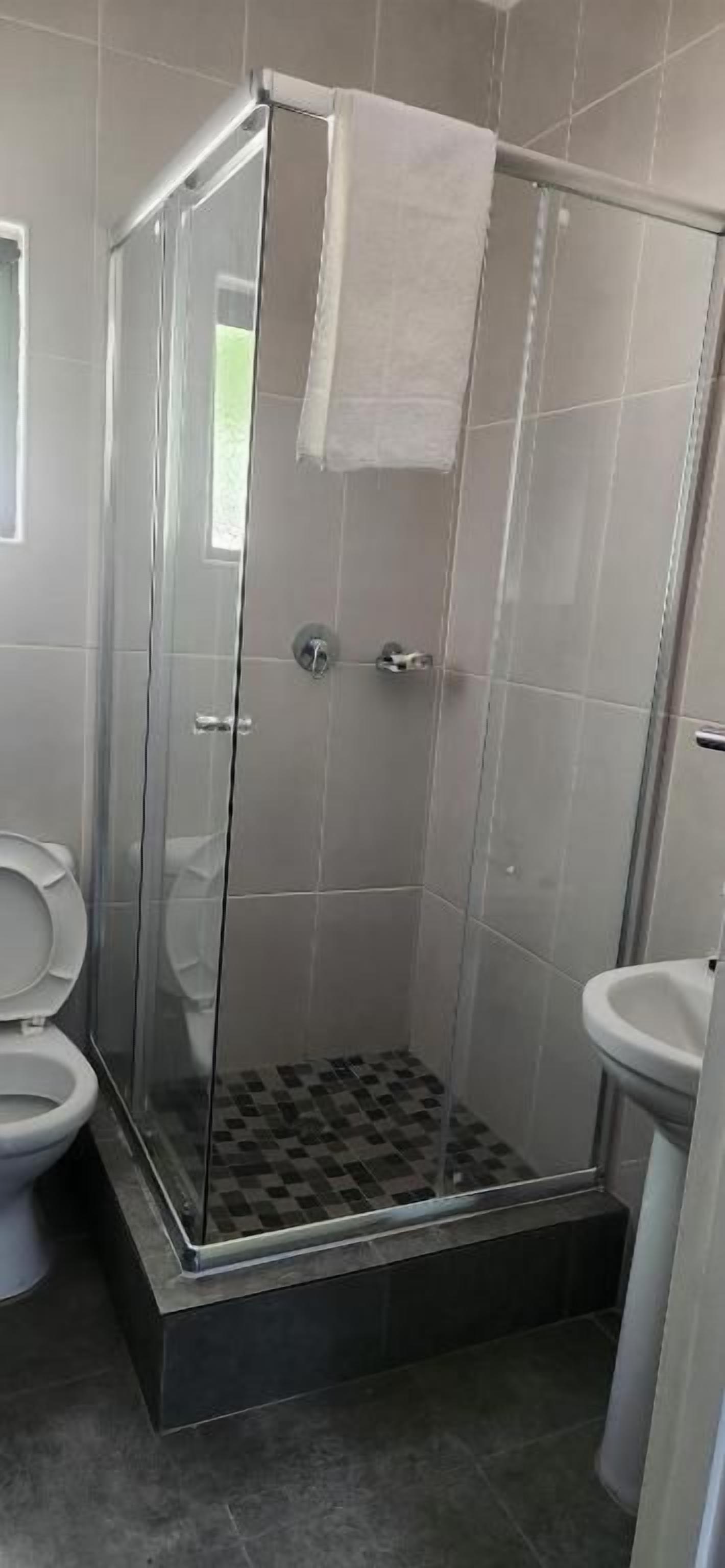 A shower enclosure with a glass door, a toilet, and a sink.