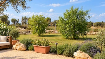 A garden with a wooden bench, potted plants, and a large rock.