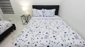A bedroom with a bed, a bedside table with a lamp, and a nightstand. - Pool Townhome 250 Steps to Beach (South Padre Island)