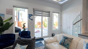 A living room with a white couch, blue armchair, and a large plant. - Sleeps 12, Pool, Walk to Beach (South Padre Island)