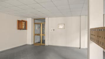 En hall med ett klinkergolv, en trädörr och ett väggmonterat skåp.