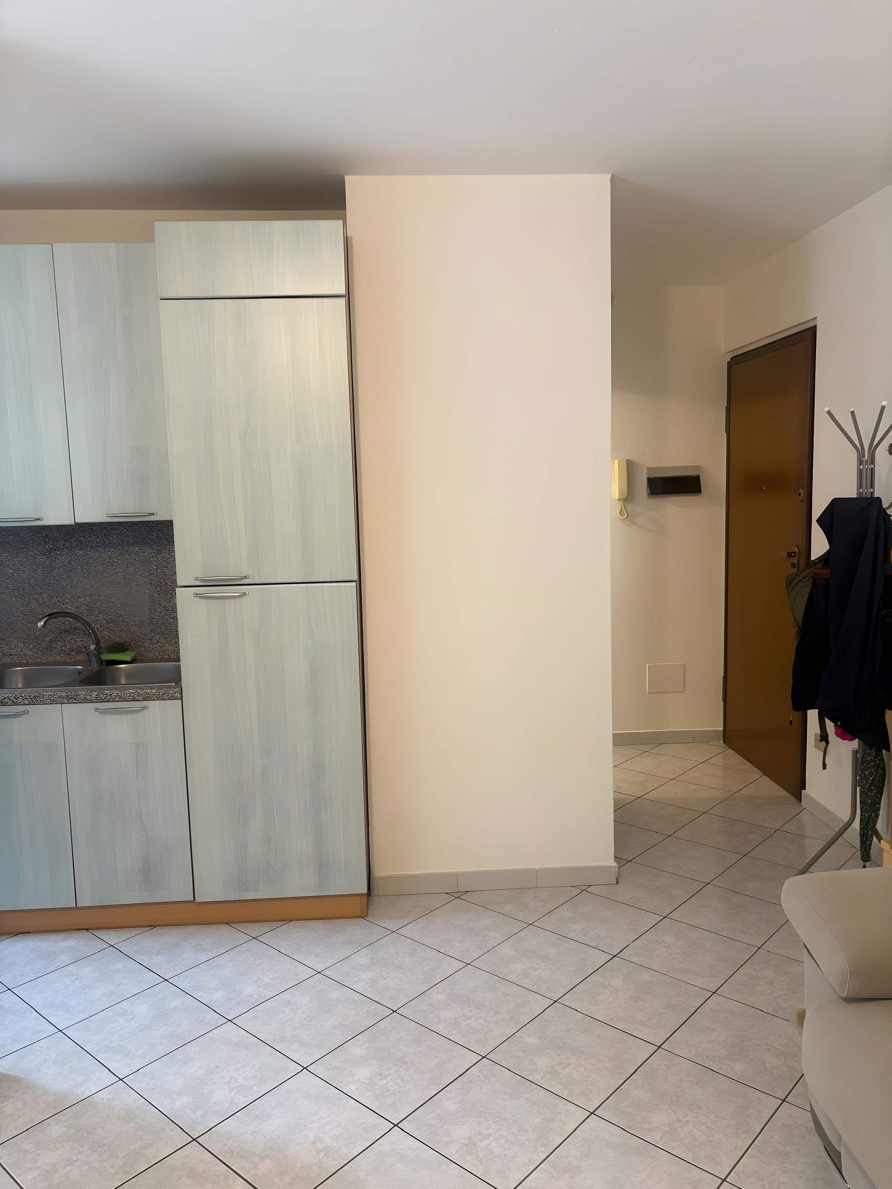 Une petite cuisine équipée d’un évier, de placards et d’une porte donnant sur une autre pièce.