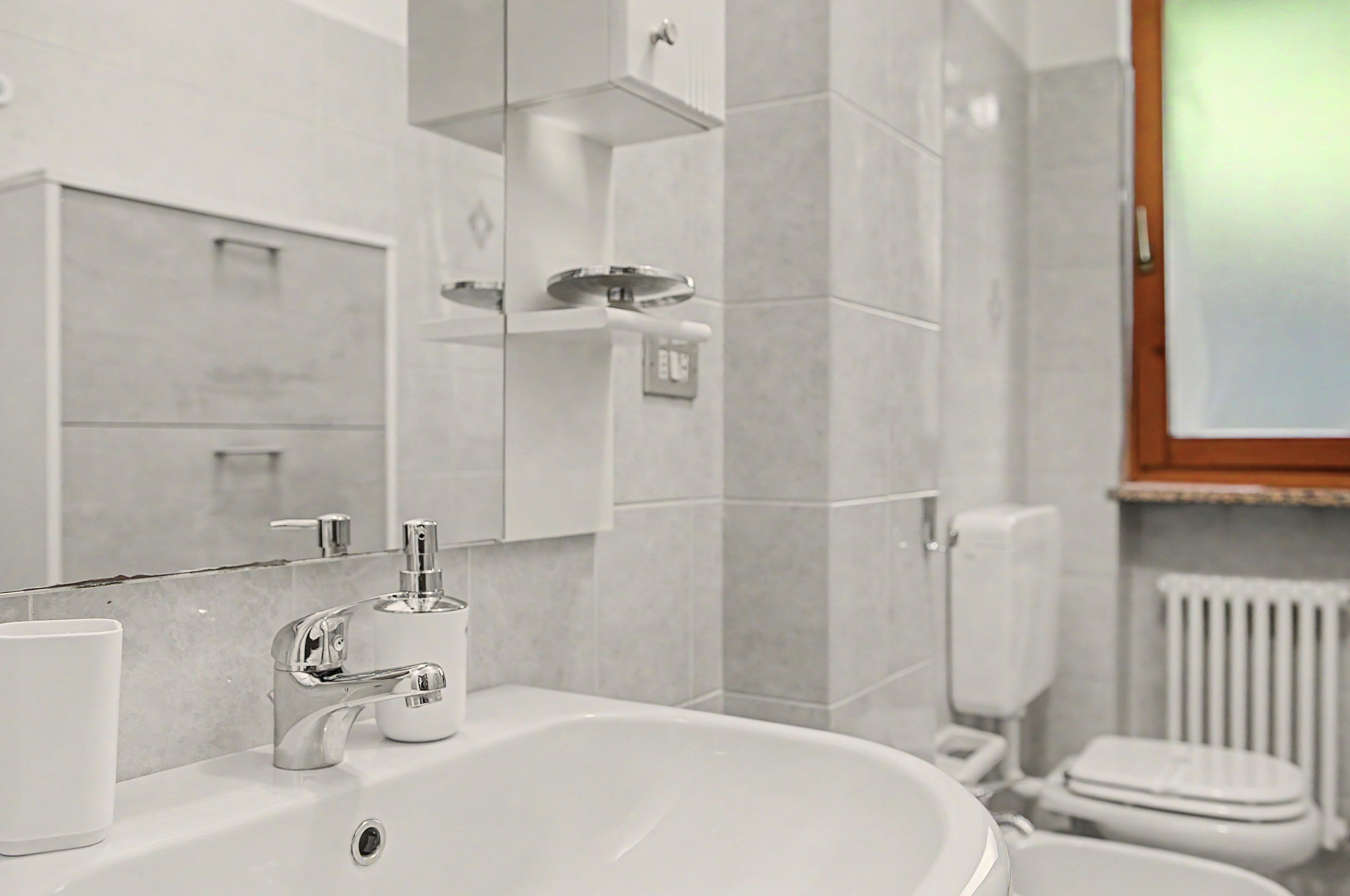 Ein Badezimmer mit einem weißen Waschbecken, einem Spiegel und einer Toilette.