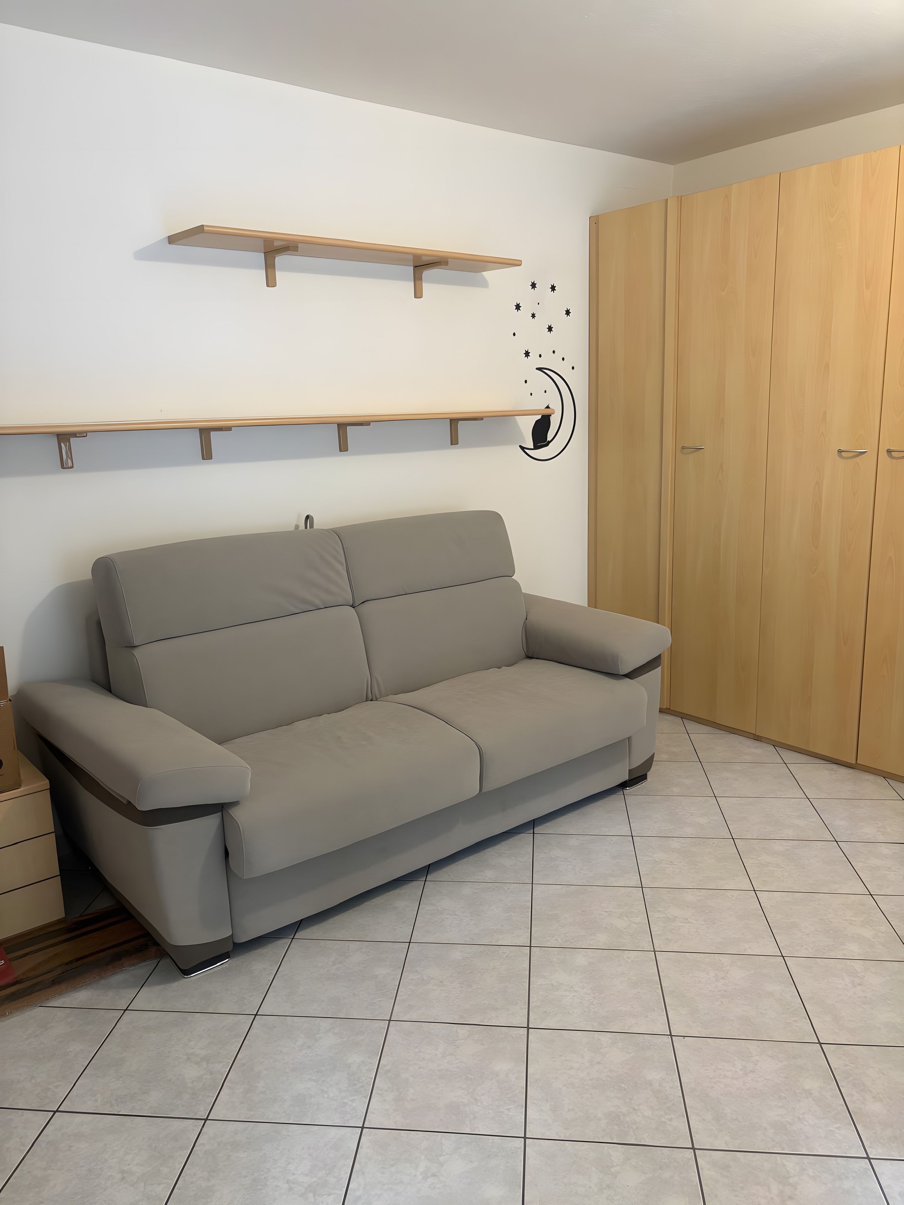 Une pièce comprenant un canapé, une armoire en bois et une étagère fixée au mur.