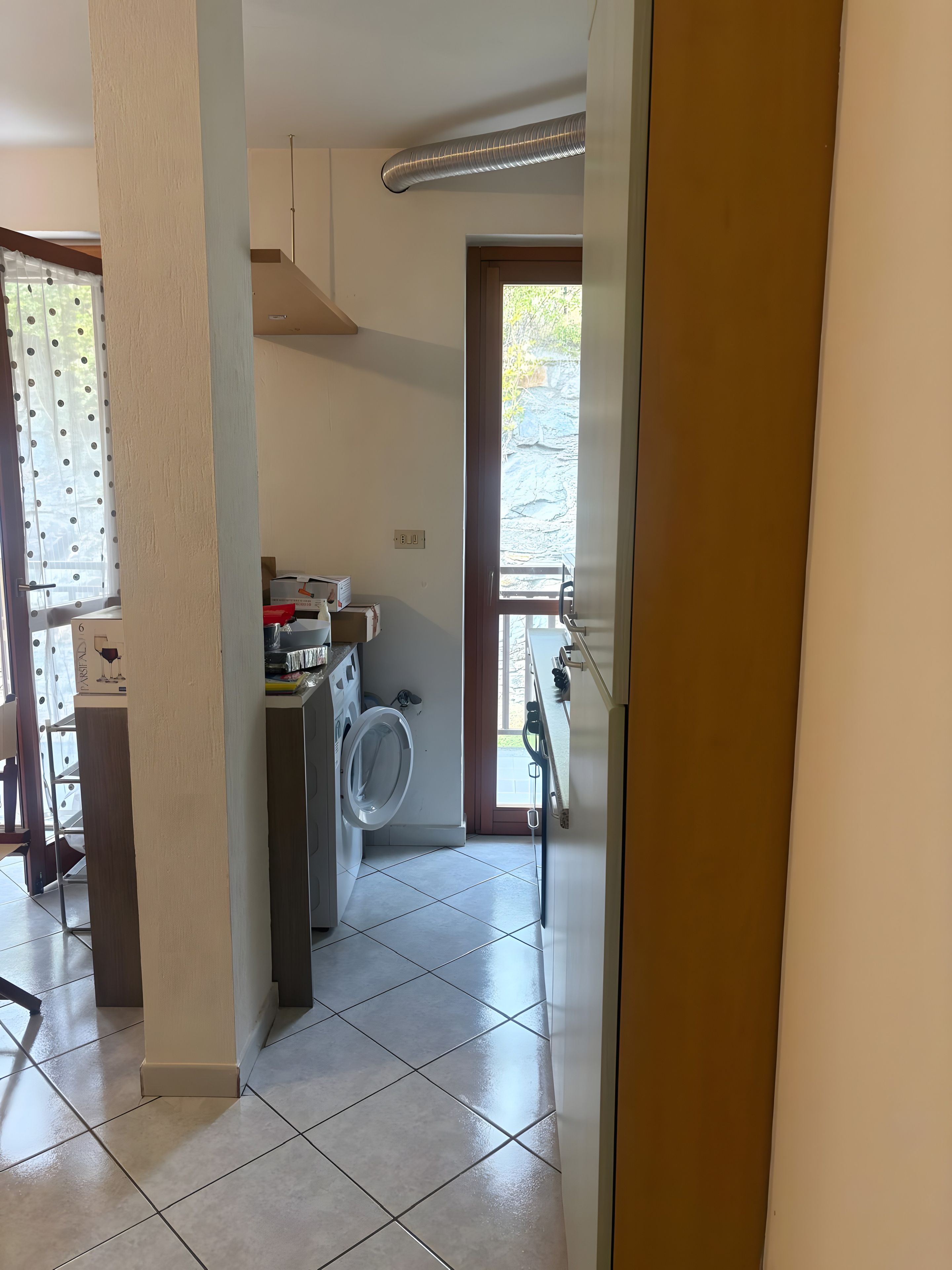 A laundry room with a washing machine, a dryer, and a window leading to an outdoor area.