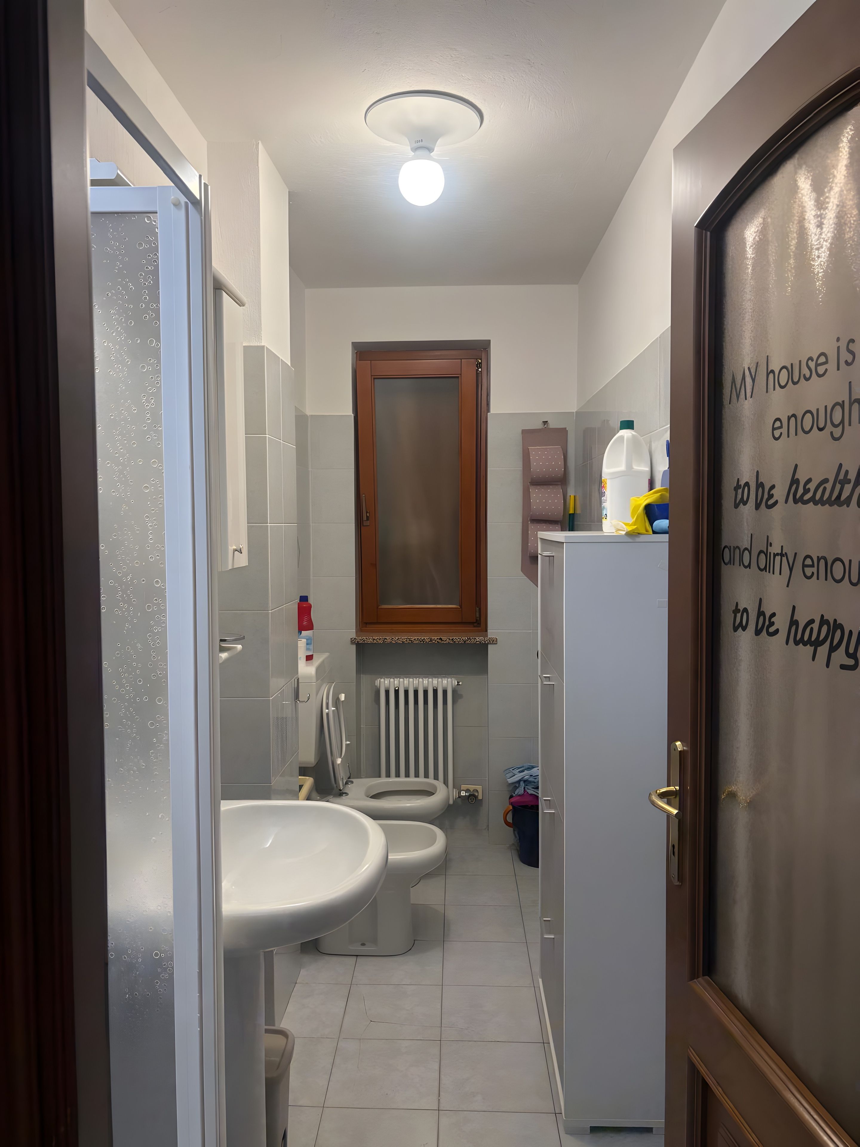 Ein Badezimmer mit zwei Toiletten, einem Waschbecken, einem Spiegel und einem Schrank.