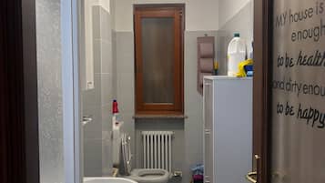 Ein Badezimmer mit zwei Toiletten, einem Waschbecken, einem Spiegel und einem Schrank.