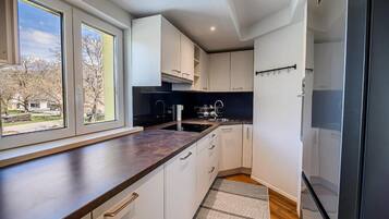 Cocina moderna con armarios blancos, encimera oscura y ventana con vistas a una zona residencial.