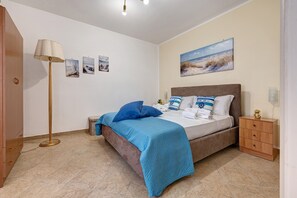 Una camera da letto con un letto, un comodino, una lampada e una parete con tre quadri.