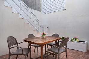 Un coin repas avec une table en bois et quatre chaises, un escalier et un radiateur blanc.