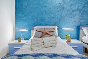 A hotel room with a bed, two bedside tables, a starfish decoration, a towel, and a plant. - Holiday Home 'Blue Wave' (Porto Cesareo)
