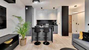 A modern kitchen with a central island, bar stools, and a dining area with a sofa and a coffee table.