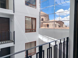 A modern building with a balcony, large windows, and a view of historical architecture. - CASA DREAMS CUSCO (Cusco)