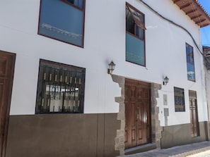 A building with a white facade, large wooden doors, and barred windows. - CASA DREAMS CUSCO (Cusco)
