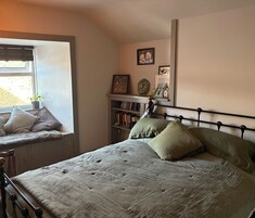 Un dormitorio con cama, ventana, estantería y adornos en la pared.