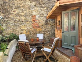 Un muro de piedra, una puerta de madera y una mesa con sillas en un patio.