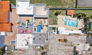 Vue aérienne d’un hôtel à plusieurs étages, doté d’une piscine et d’espaces de détente en plein air.