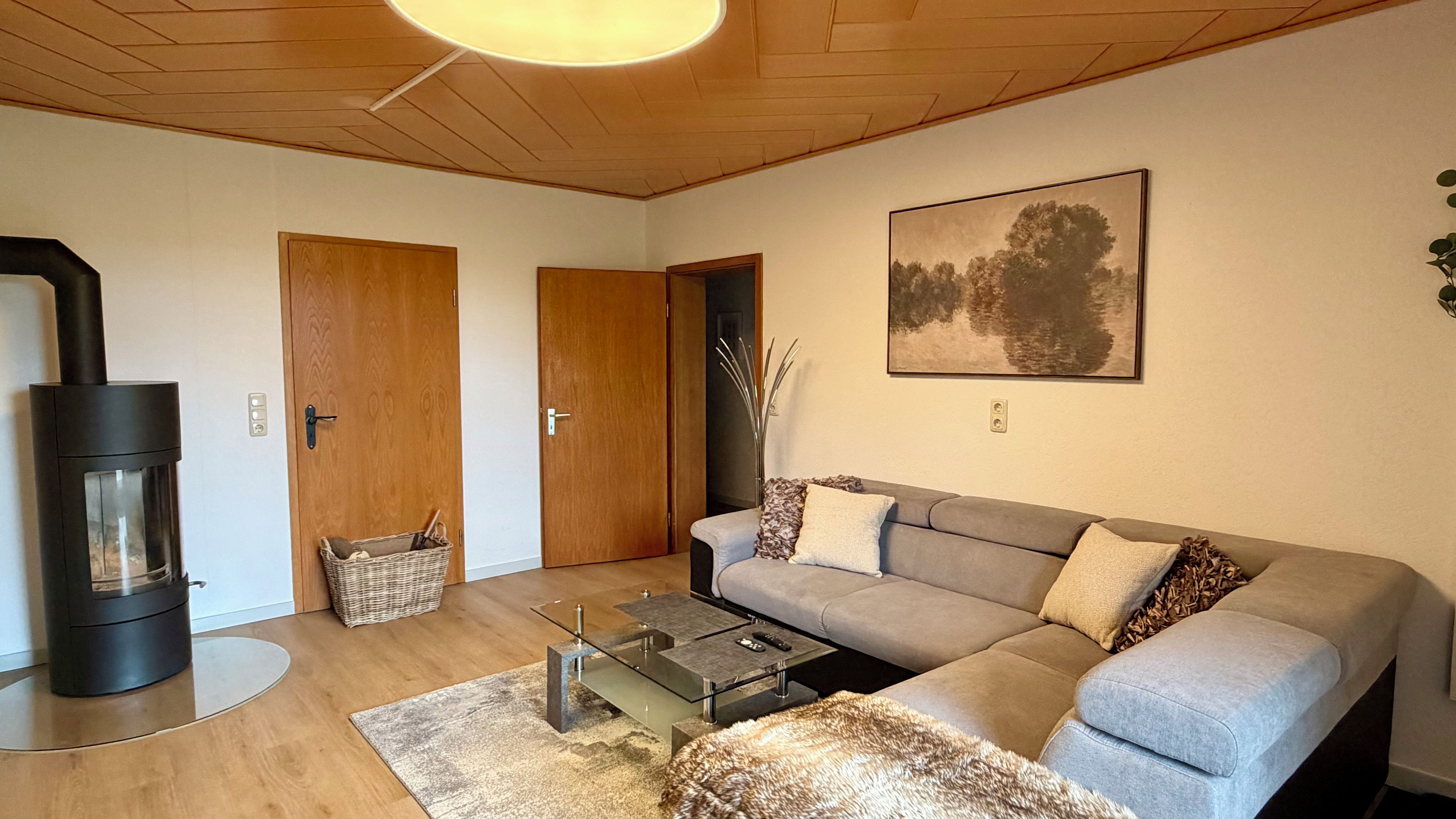 Un salon avec un canapé, une table basse en verre, une cheminée et un tableau au mur.