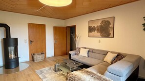 Un salon avec un canapé, une table basse en verre, une cheminée et un tableau au mur.