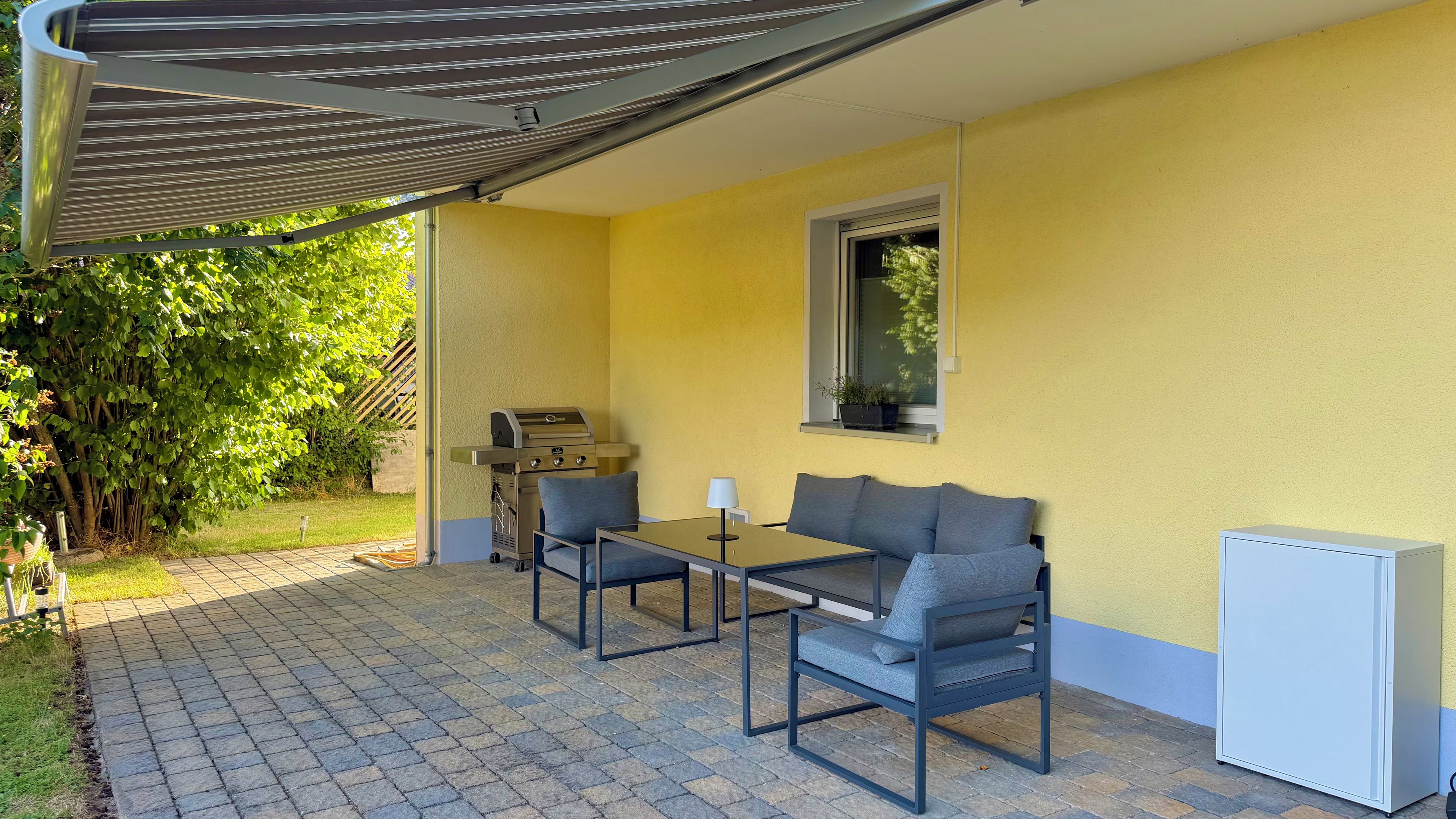 A patio with a grill, a table, and two chairs.