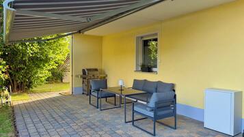 A patio with a grill, a table, and two chairs.
