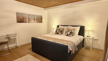 Ein Schlafzimmer mit einem Bett, Nachttischlampen, einem Schreibtisch und einem Stuhl.