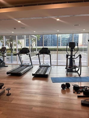 A gym with treadmills, a stationary bike, and weights. - Burj Khalifa View Apartment at Vera Residences (Dubai)
