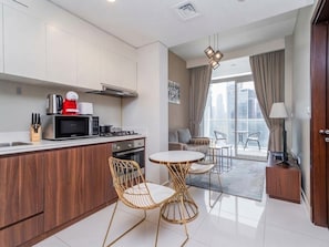 A modern kitchen with a dining area, a sofa, and a view of the city. - Burj Khalifa View Apartment at Vera Residences (Dubai)