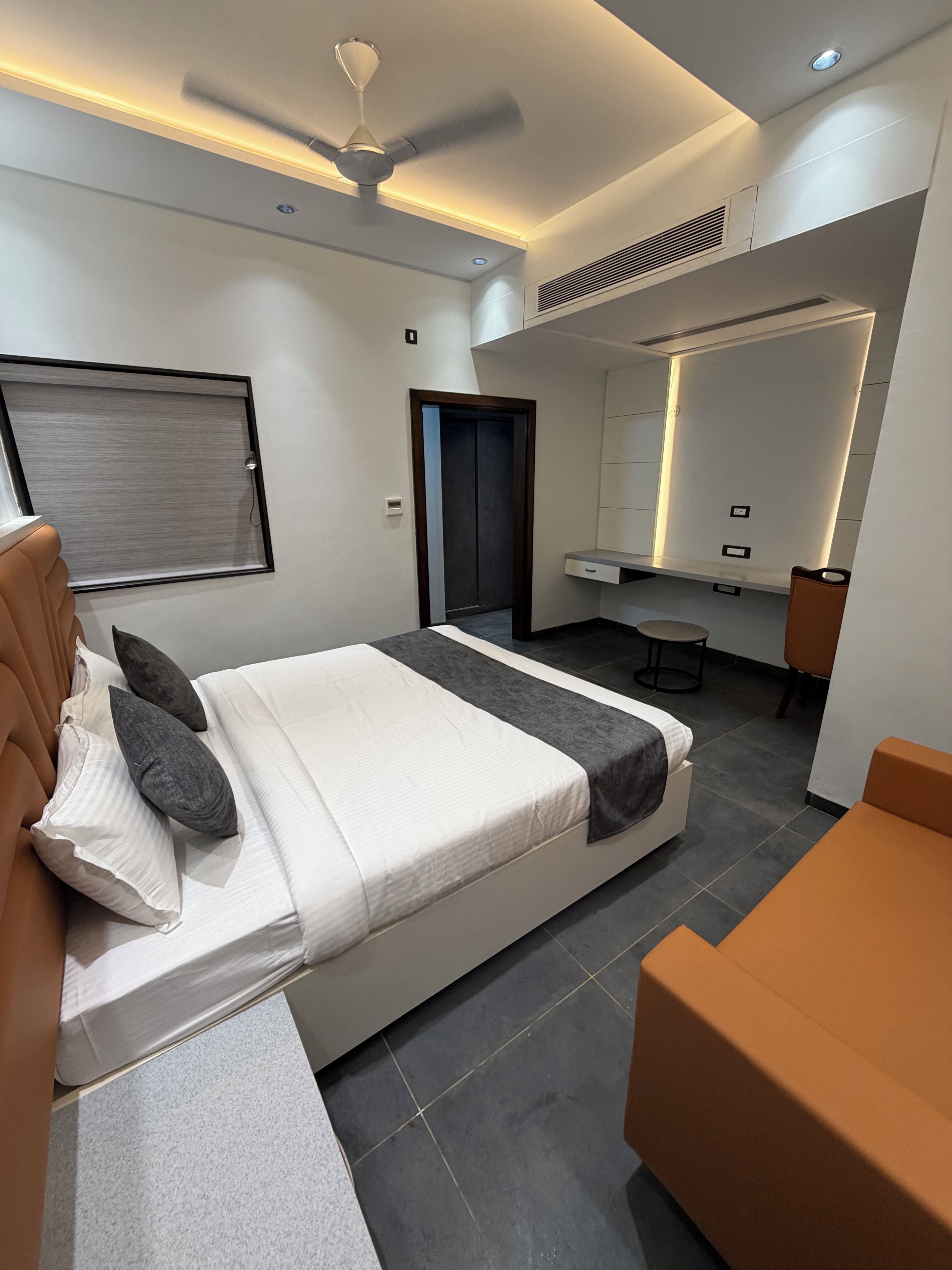 Una habitación de hotel moderna con cama, escritorio, silla y espejo.