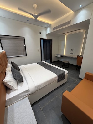 Una habitación de hotel moderna con cama, escritorio, silla y espejo.