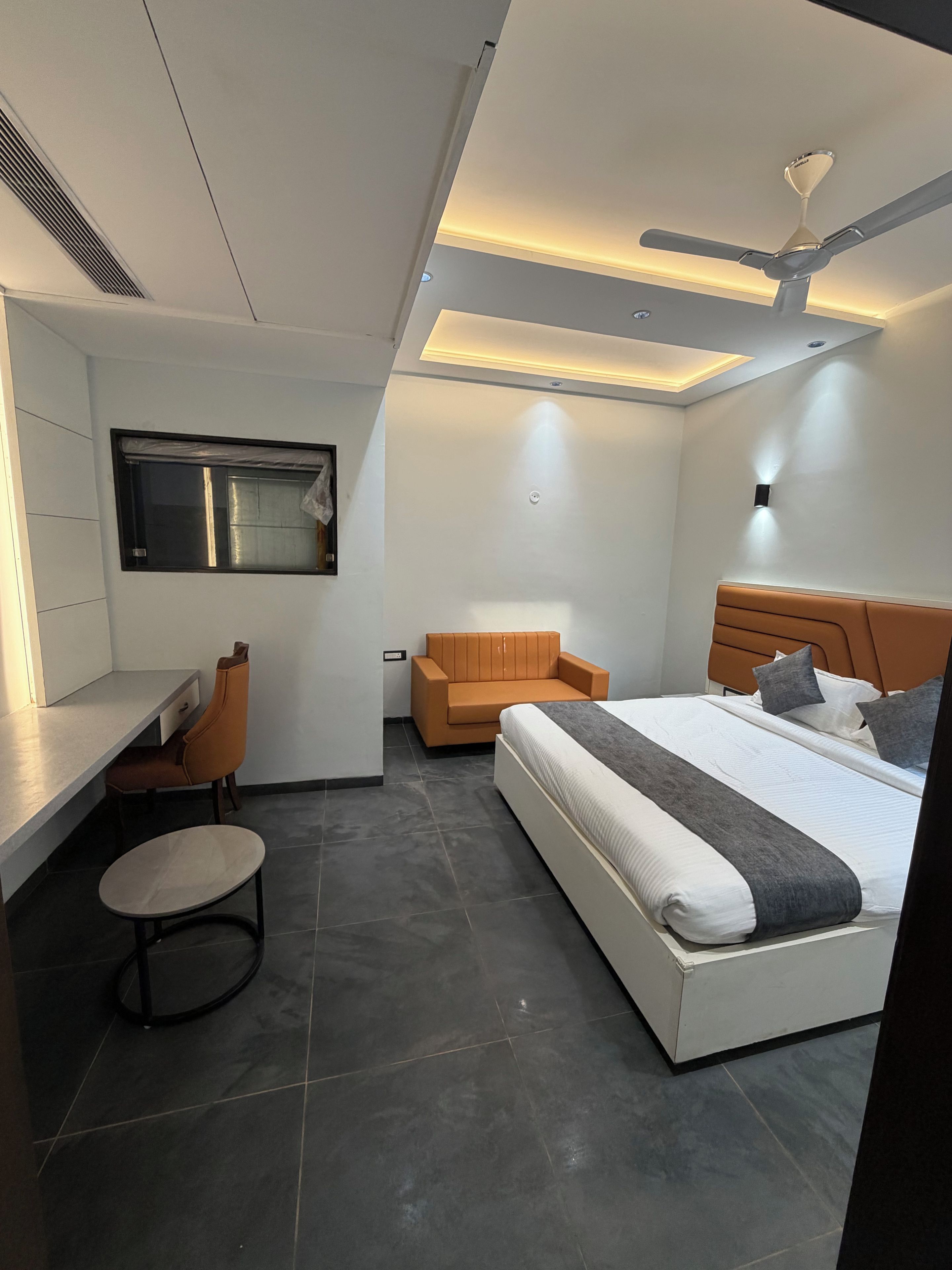 Un dormitorio moderno con cama, escritorio, silla y ventilador de techo.