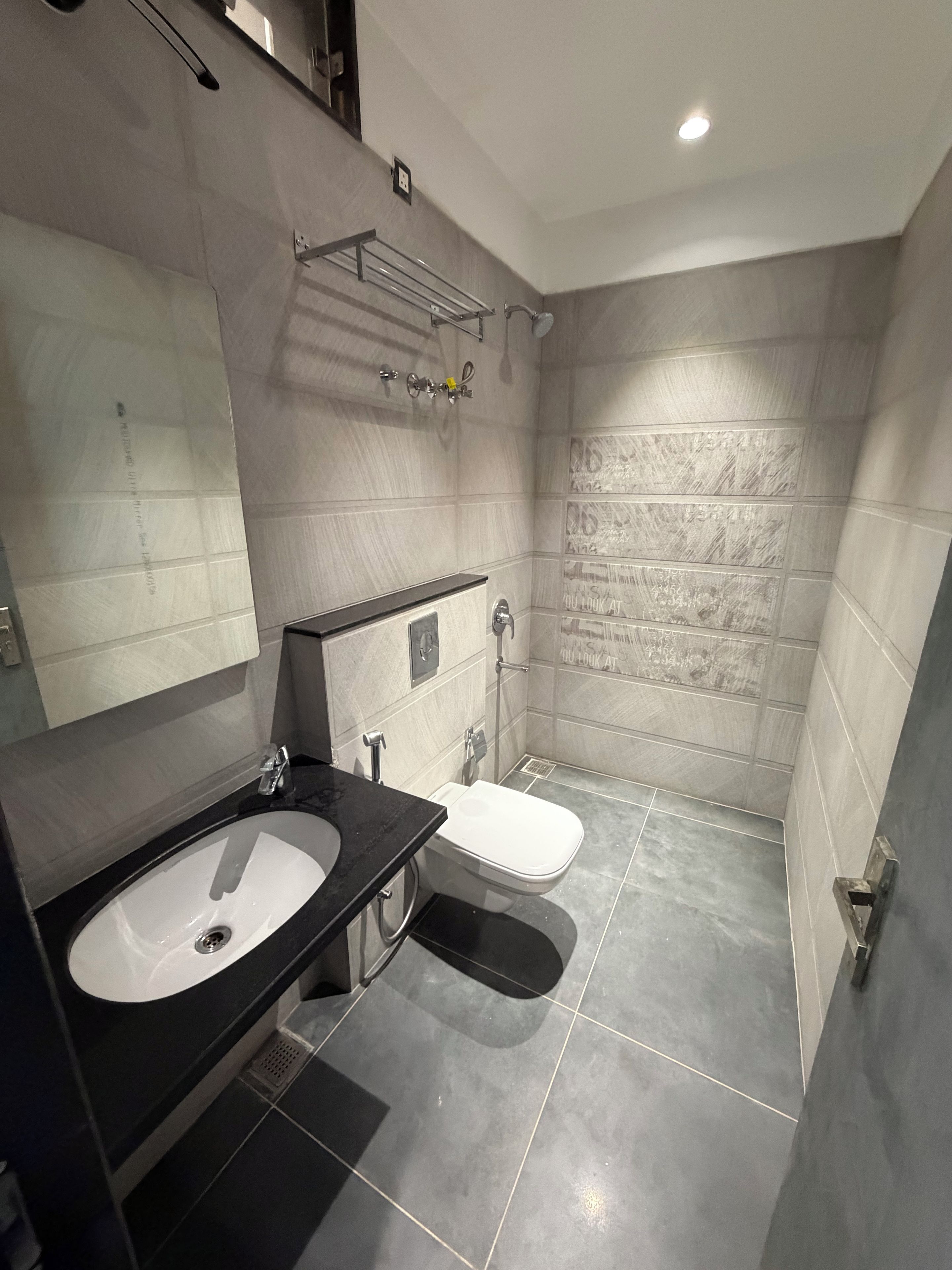 Un baño moderno con un espejo grande, un lavabo, un inodoro y una zona de ducha.