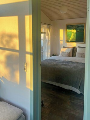 A bedroom with a bed, a painting, and a window with curtains. - Idyll and charm with views over the fjord (Kalundborg)