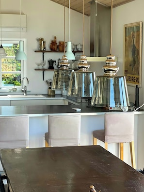 A modern kitchen with a central island, pendant lights, and a view of the outdoors. - Idyll and charm with views over the fjord (Kalundborg)
