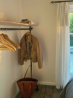 Une pièce dans laquelle on aperçoit un portant à vêtements avec une veste, un sac et un vêtement plié.