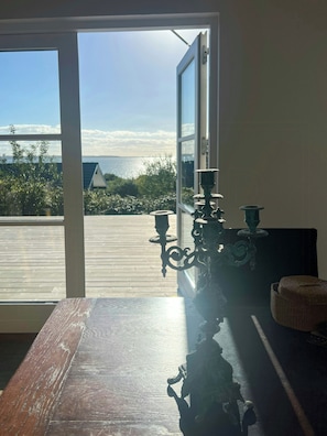 A room with a view of the sea through a large window, a wooden table, and a decorative metal chandelier. - Idyll and charm with views over the fjord (Kalundborg)