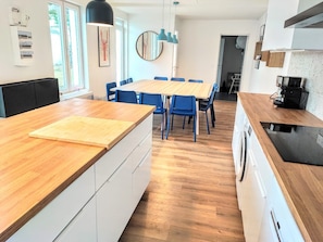 Una cocina moderna con encimera de madera, un comedor con sillas azules y una isla grande.