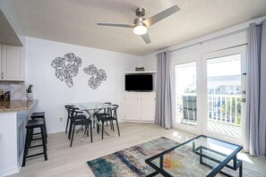 A modern living space with a dining area, a flat-screen TV, and a balcony with curtains. - Summer Breeze 310 (Miramar Beach)