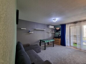 A living room with a sofa, a small table, a flat-screen TV, and a ceiling light fixture. - Charming apartment near downtown (Avignon)