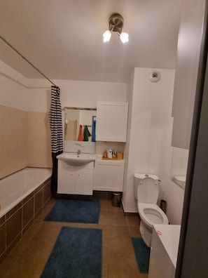 A bathroom with a bathtub, sink, toilet, and a shower curtain. - Charming apartment near downtown (Avignon)