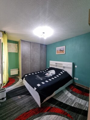 A bedroom with a bed, a radiator, a wardrobe, and a picture on the wall. - Charming apartment near downtown (Avignon)