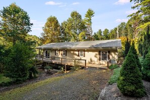 A single-story house with a porch, surrounded by dense forest. - Riverside Cabin, Mtn Views, Fire Pit and Fireplace (West Jefferson)