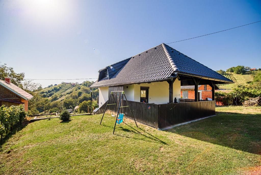 Una casa con techo inclinado, patio cercado y vista despejada de las colinas circundantes.