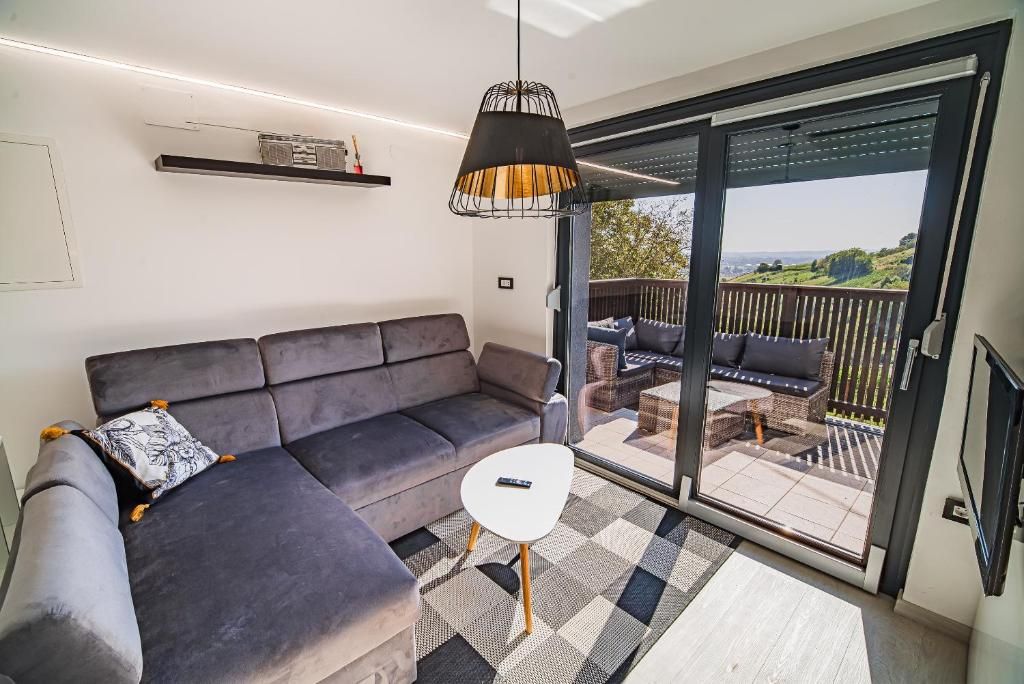 A modern living room with a grey sectional sofa, a small white side table, and a hanging pendant light.