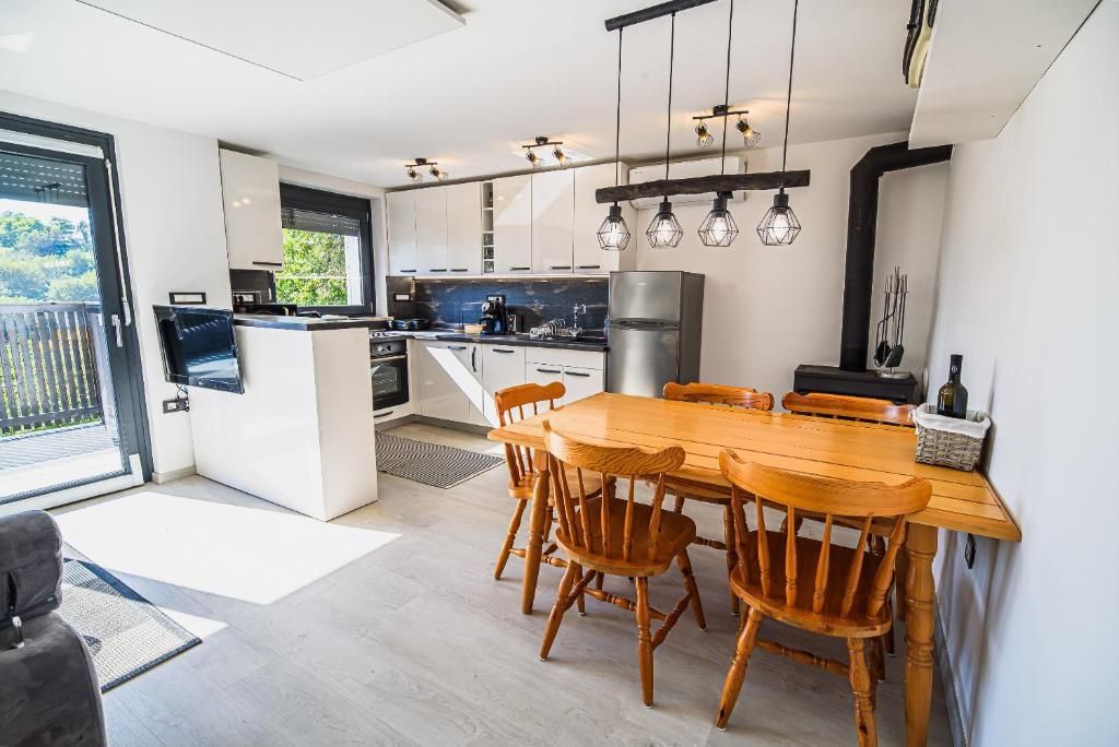 Cocina moderna con comedor, que cuenta con una isla central, sillas de madera e iluminación colgante.