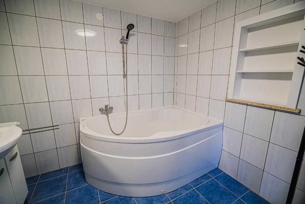 Un baño con una bañera independiente, cabezal de ducha y un lavamanos blanco.