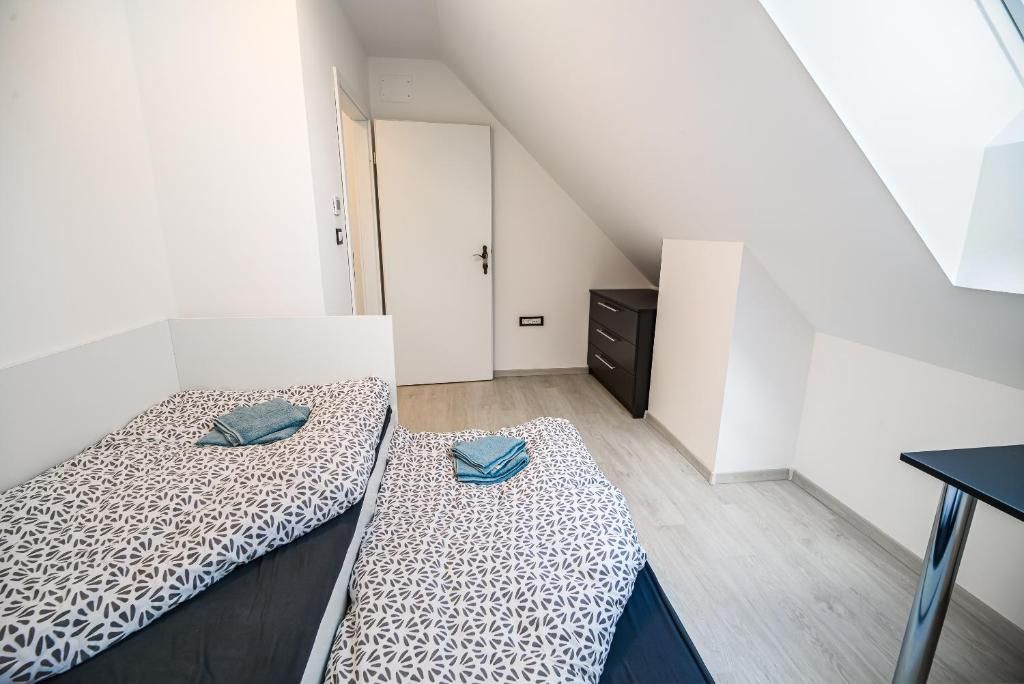 A small, modern room with two beds, a desk, and a wardrobe.