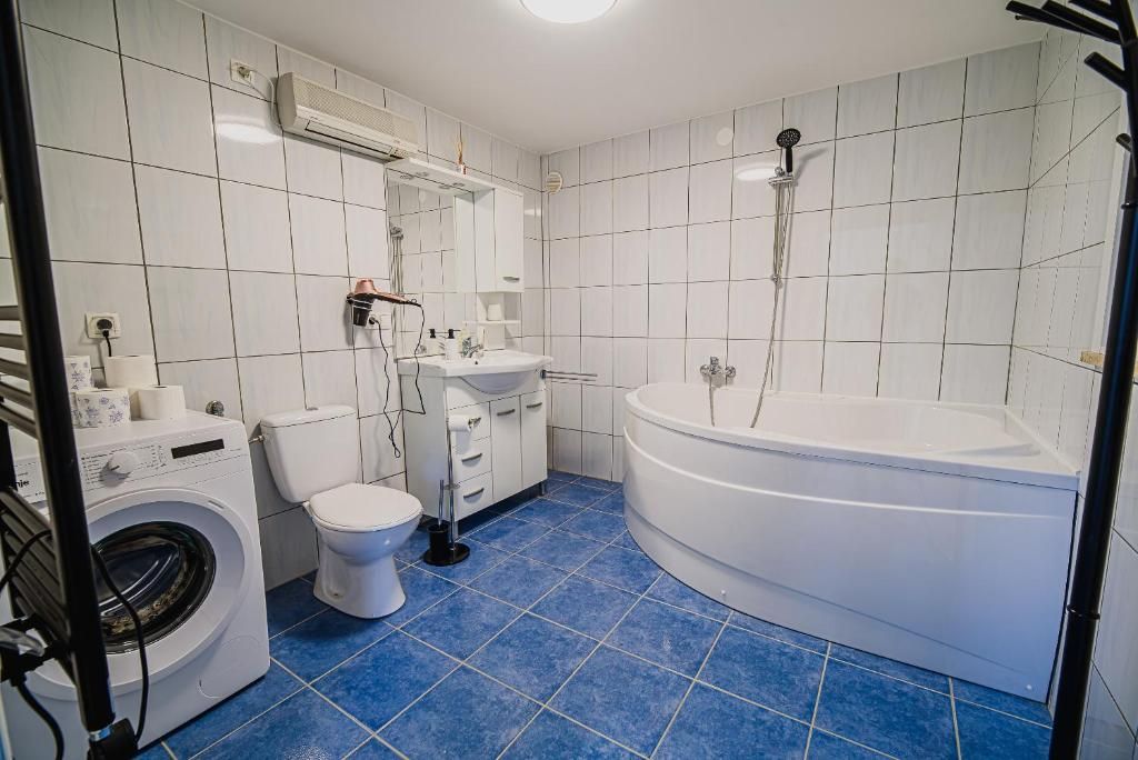 A bathroom with a washing machine, toilet, sink, and bathtub.